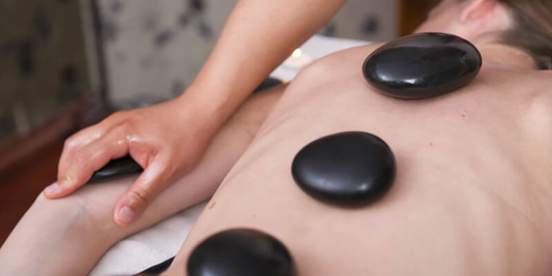 Tratamiento de spa con piedras sobre la espalda y brazos Tratamiento de spa con piedras sobre la espalda y brazos